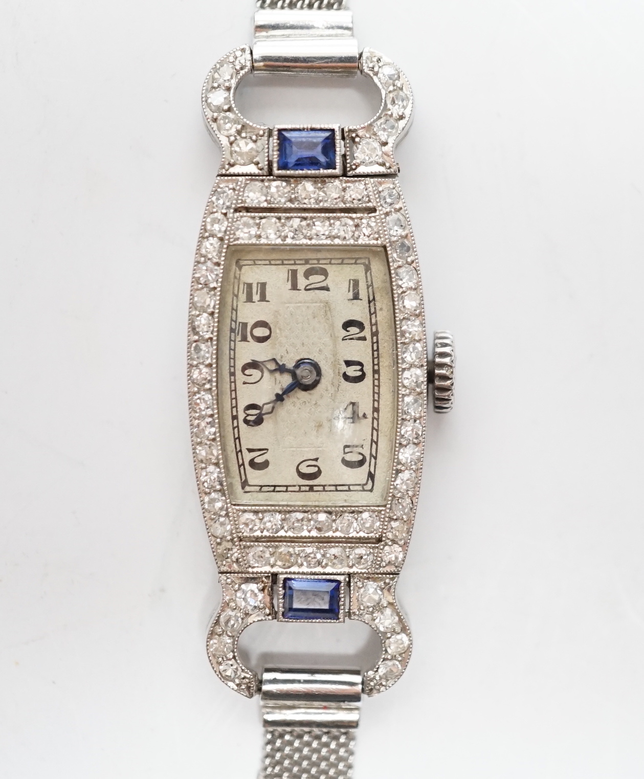 A lady's mid 20th century white metal (Swiss platinum mark), sapphire and diamond cluster set manual wind cocktail watch, with Arabic dial, on and adjustable 9ct mesh link bracelet, gross weight 18 grams.